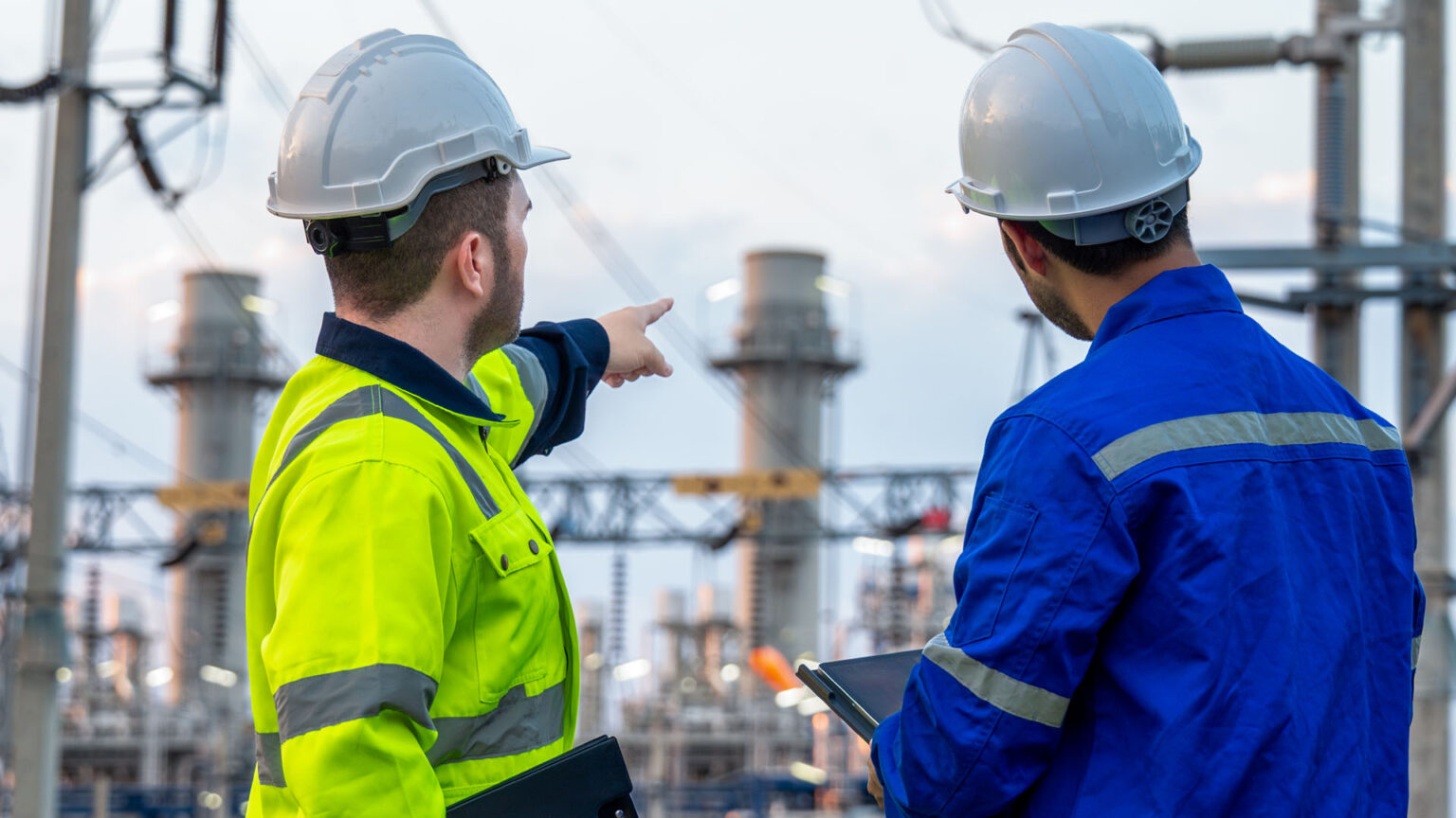 Two engineers pointing at a substation